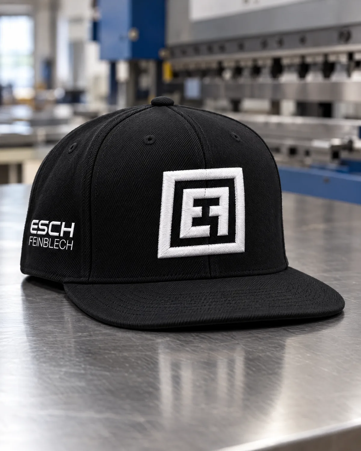 Schwarze Snapback mit erhabenem 3D-Stick des EF-Signets und Schriftzug Esch Feinblech an der Seite