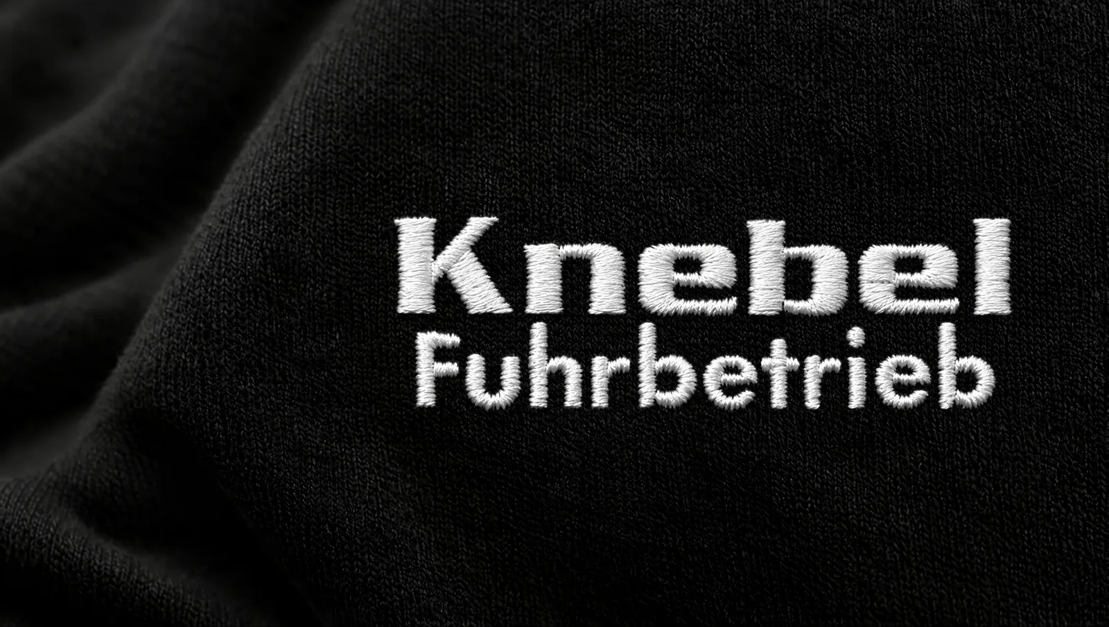 Makroaufnahme einer weißen Maschinenstickerei auf schwarzem Sweatstoff
